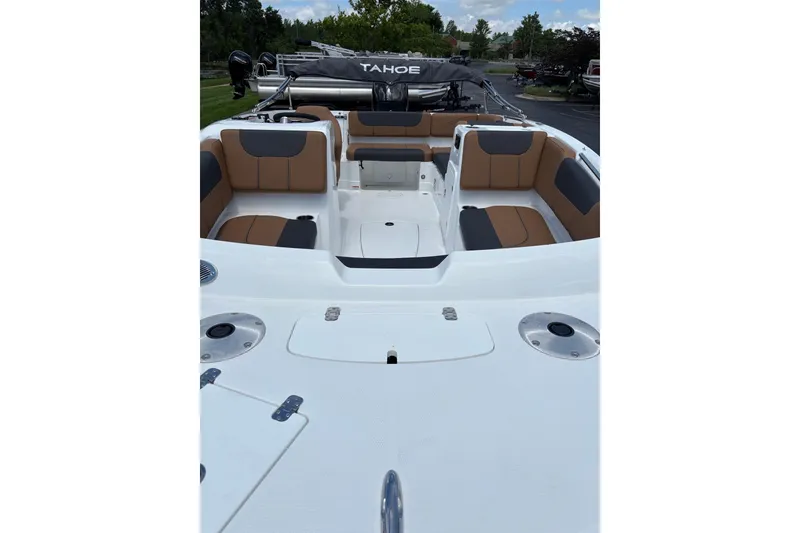 Slide: The Image of 2026 Tahoe 1950 boat interior with tan and gray seating, docked outdoors. - 2