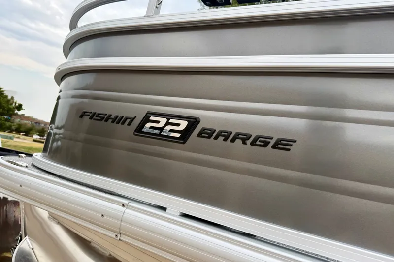 Slide: The Image of 2026 Sun Tracker Fishin' Barge 22 XP3, sleek silver exterior with bold lettering. - 13