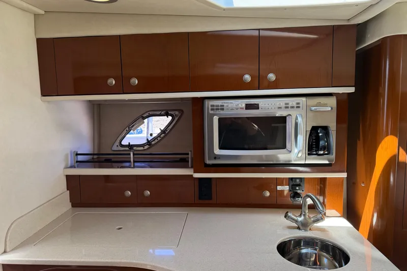 Slide: The Image of 2008 Sea Ray Sundancer 310 galley with microwave, sink, and wooden cabinetry. - 33