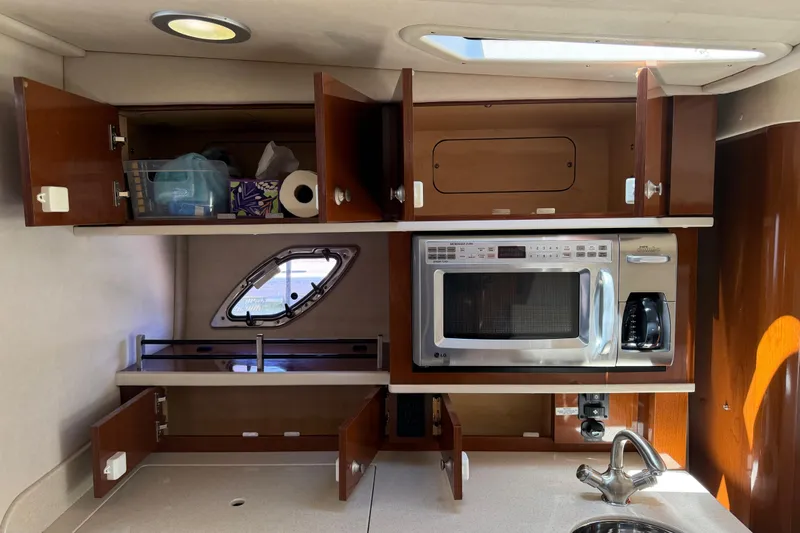 Slide: The Image of 2008 Sea Ray Sundancer 310 galley with open cabinets, microwave, and sink. - 34