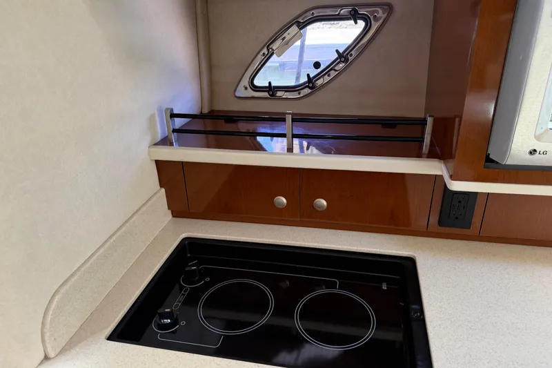 Slide: The Image of 2008 Sea Ray Sundancer 310 galley with stove, window, and wooden cabinetry. - 36