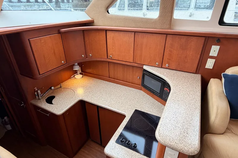 Slide: The Image of 2006 Silverton 38 Convertible yacht kitchen with wood cabinets, countertop, sink, and built-in appliances. - 15