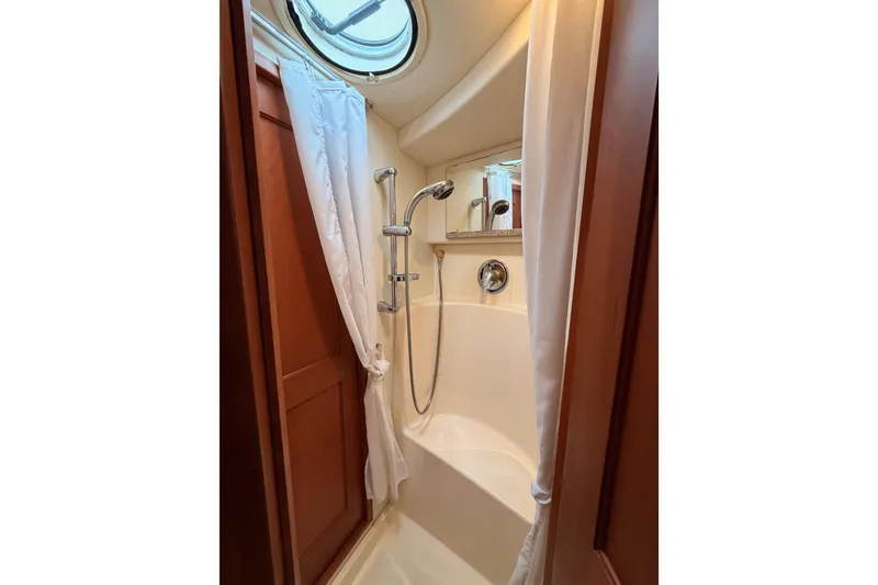 Slide: The Image of 2006 Silverton 38 Convertible yacht bathroom with shower, curtain, and porthole window. - 19