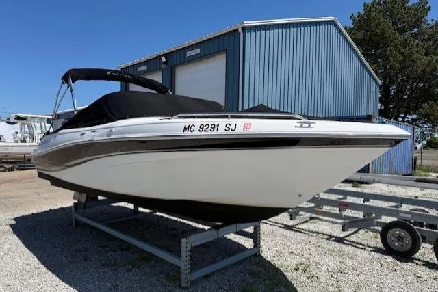 Slide: The Image of 2002 Four Winns 220 Horizon boat on trailer, parked near blue building. - 0