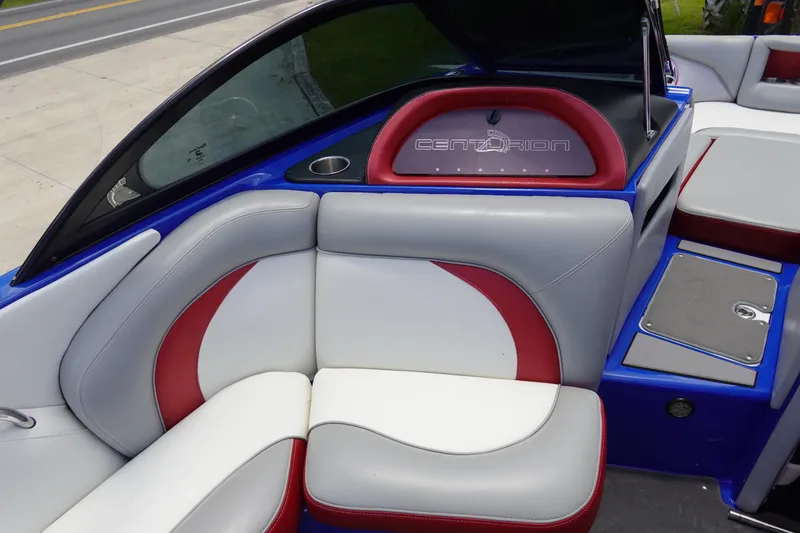 Slide: The Image of 2013 Centurion Enzo SV244 boat interior with red and white seating, cup holder, and logo. - 11