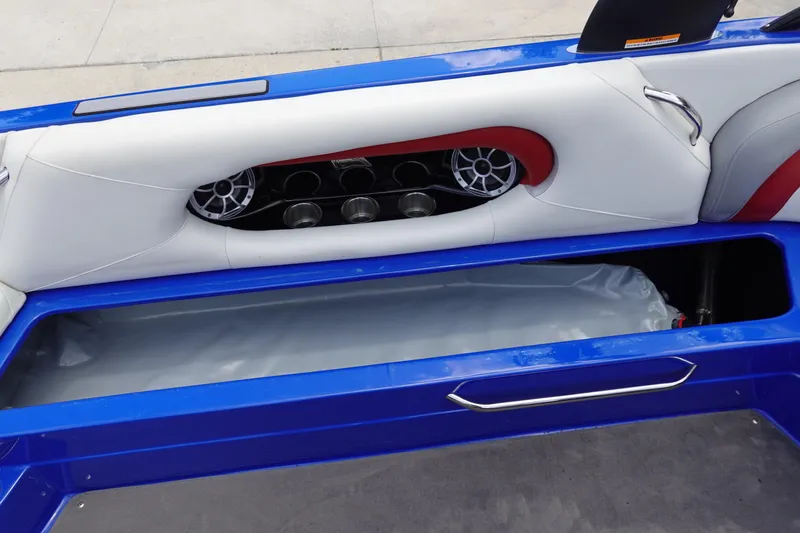 Slide: The Image of 2013 Centurion Enzo SV244 boat interior with blue and white seating, speaker, and storage compartment. - 16