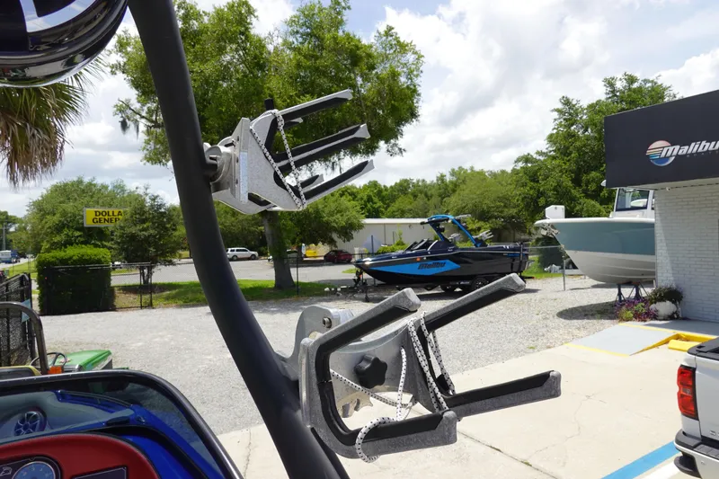 Slide: The Image of 2013 Centurion Enzo SV244 boat with wakeboard racks, parked near Malibu Boats dealership. - 21