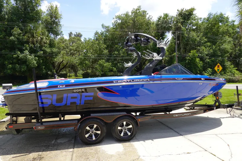Slide: The Image of 2013 Centurion Enzo SV244 boat on trailer, blue and black design, parked outdoors. - 4