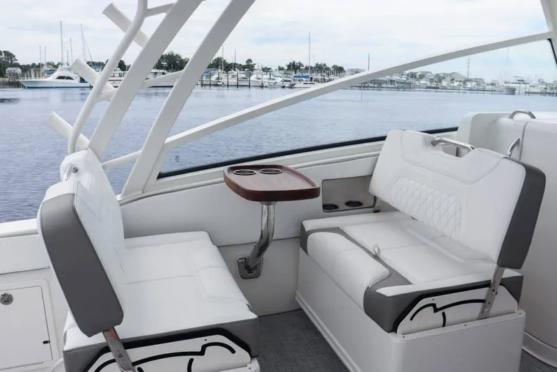 Slide: The Image of Manufacturer Provided Image: 2026 World Cat 325 DC boat interior with white seating and a wooden table, docked at marina. - 6