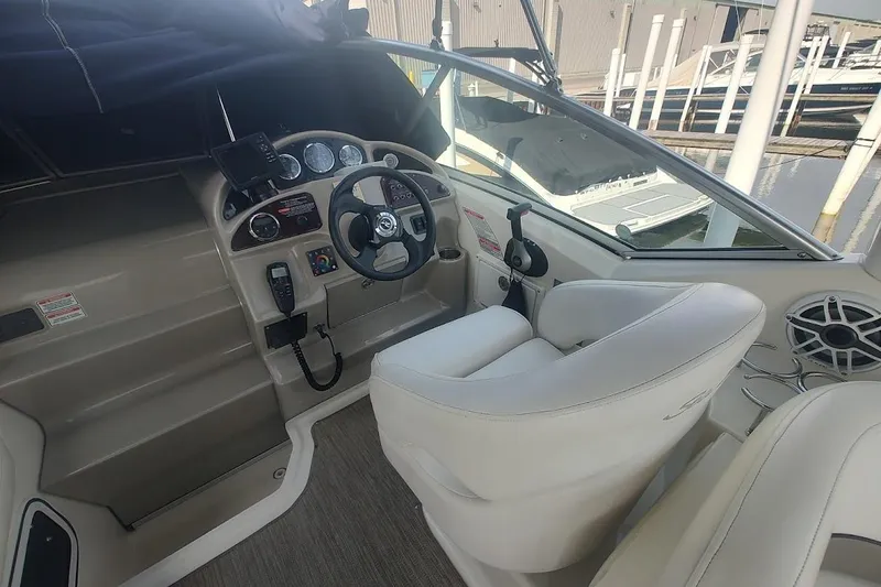 Slide: The Image of 2006 Sea Ray Sundancer 260 cockpit with steering wheel, controls, and white seating at marina. - 14