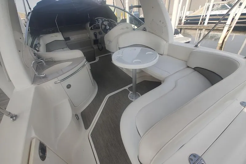 Slide: The Image of 2006 Sea Ray Sundancer 260 interior with seating, table, and helm, docked at marina. - 16