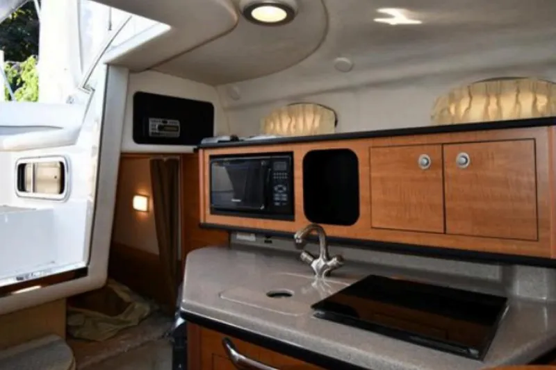 Slide: The Image of 2006 Sea Ray Sundancer 260 cabin interior with kitchenette, featuring microwave and sink. - 5
