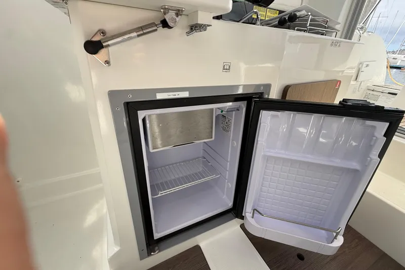 Slide: The Image of Open refrigerator inside a 2021 Beneteau Antares 8 boat, showcasing interior storage space. - 16