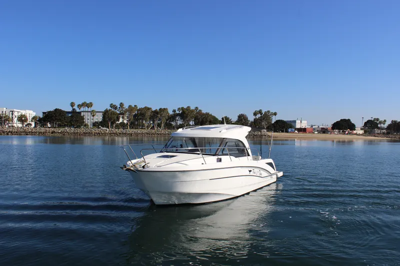 Slide: The Image of 2021 Beneteau Antares 8 boat cruising on calm water near a scenic shoreline. - 3