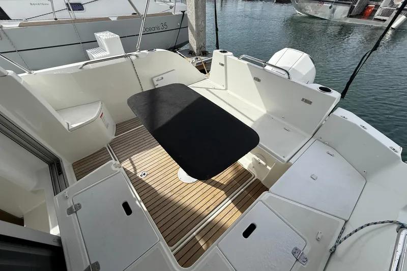 Slide: The Image of 2021 Beneteau Antares 8 boat deck with seating and table, docked at marina. - 9