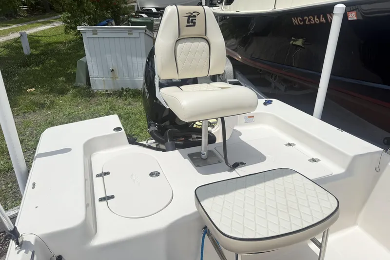Slide: The Image of 2023 Carolina Skiff 162 JLS boat interior with cushioned seating and storage compartments. - 7