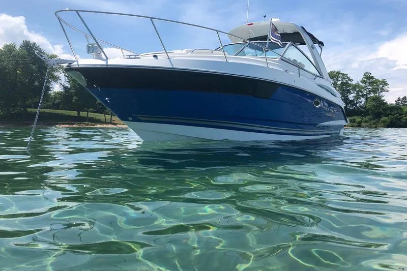 Slide: The Image of 2018 Monterey 295 Sport Yacht on clear water, anchored near a lush shoreline. - 1