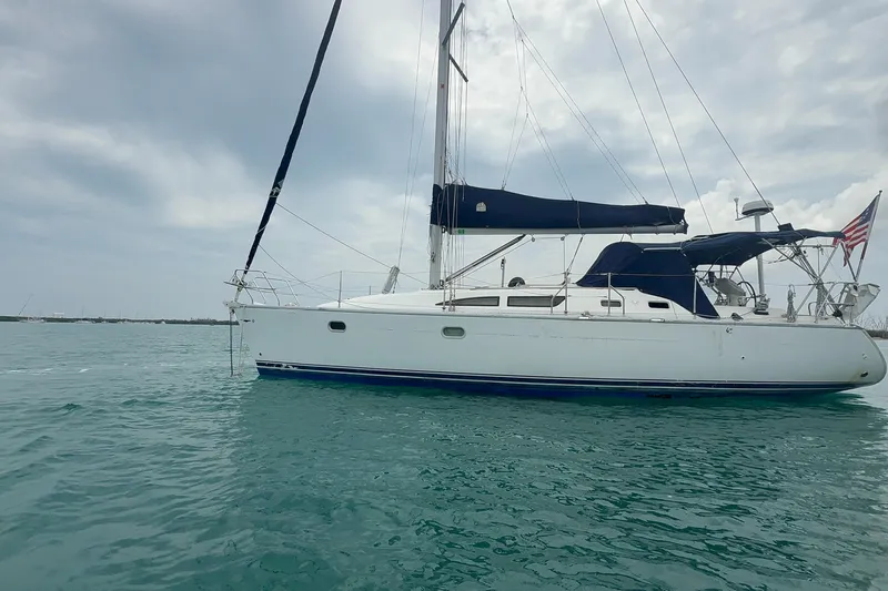 The Image of 2003 Jeanneau Sun Odyssey 37 sailboat on calm blue water under cloudy sky. - 1