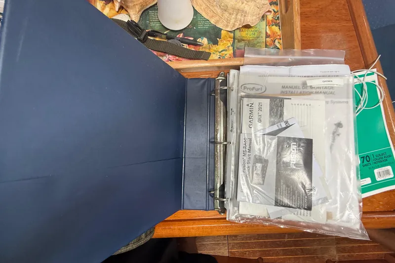 Slide: The Image of Open binder with manuals for Jeanneau Sun Odyssey 37, 2003 model, on a wooden table. - 114