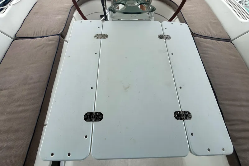 Slide: The Image of Cockpit table on a 2003 Jeanneau Sun Odyssey 37 sailboat, surrounded by cushioned seating. - 18