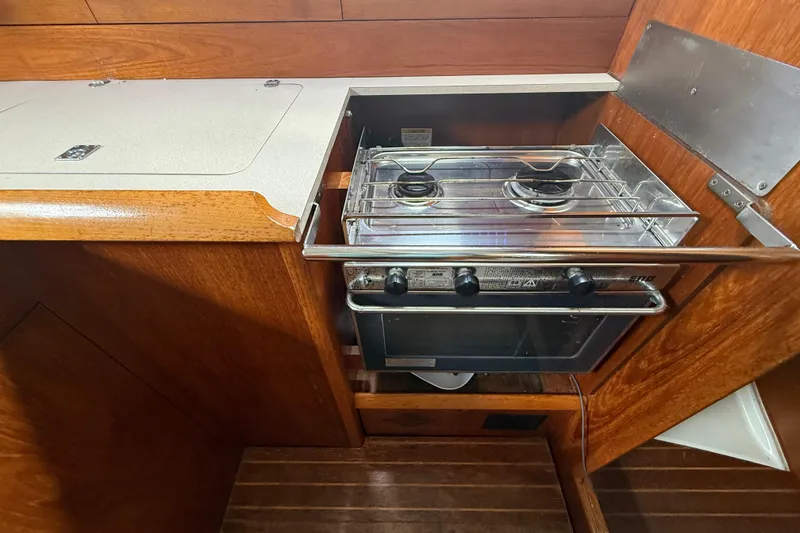 Slide: The Image of Galley kitchen in 2003 Jeanneau Sun Odyssey 37 sailboat with stove and wooden cabinetry. - 73