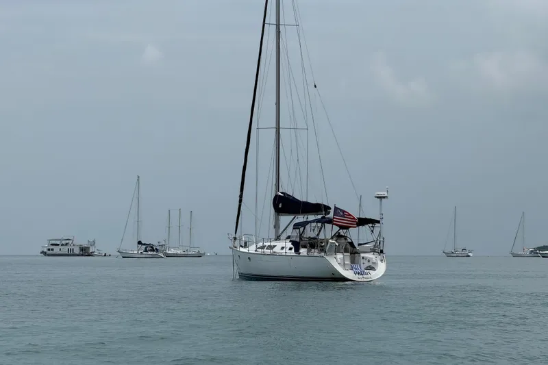 Slide: The Image of 2003 Jeanneau Sun Odyssey 37 sailboat anchored in calm waters, surrounded by other boats. - 9