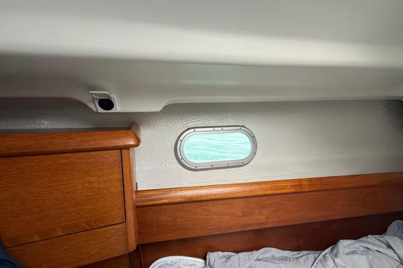 Slide: The Image of Interior cabin view of a 2003 Jeanneau Sun Odyssey 37 sailboat with wooden trim and porthole. - 90