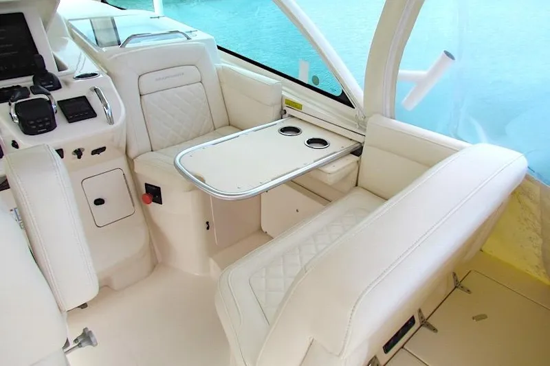 Slide: The Image of 2019 Grady-White Express 370 interior with white seating and table, featuring cup holders. - 20