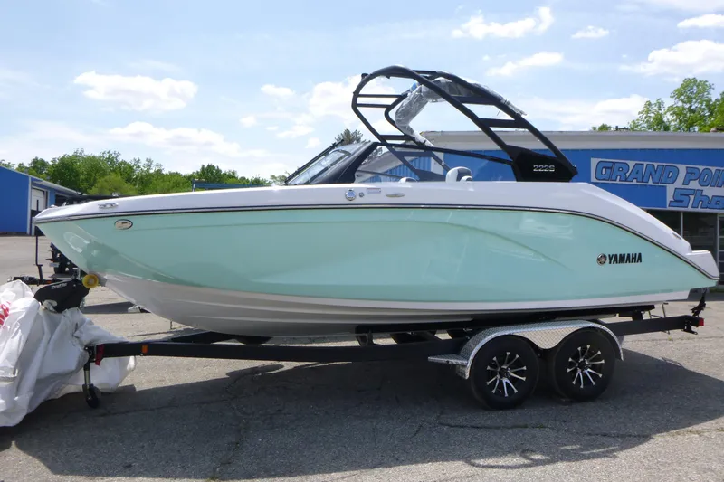 The Image of 2026 Yamaha Boats 222S on trailer, sleek design, mint green hull, parked outdoors. - 1