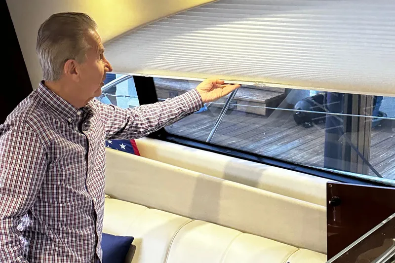 Slide: The Image of Man adjusting blinds on a 2015 Sea Ray 510 Fly yacht. - 29