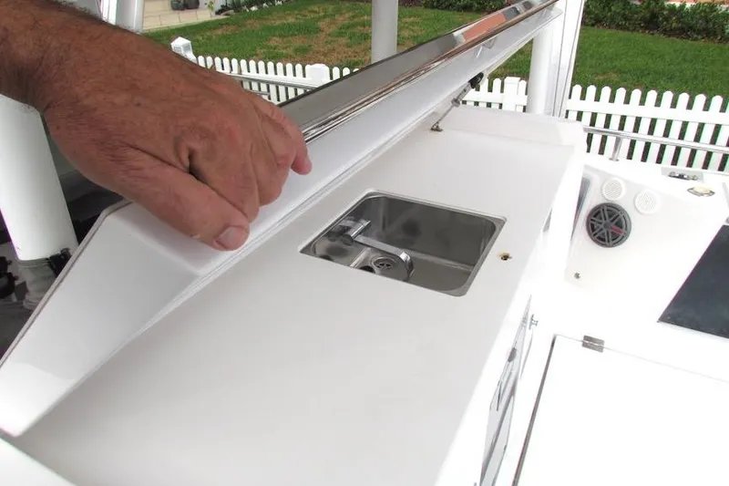 Slide: The Image of Hand opening compartment on 2018 Axopar 37 Sun-Top boat, revealing a small sink. - 18
