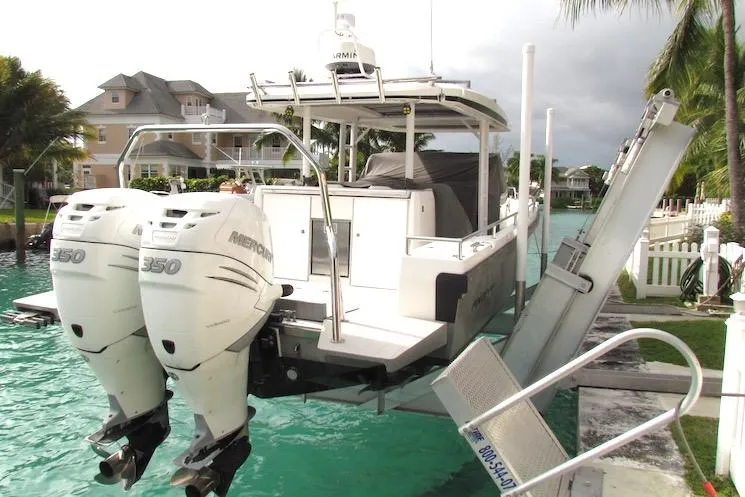 Slide: The Image of 2018 Axopar 37 Sun-Top boat with twin Mercury 350 engines docked by waterfront homes. - 2