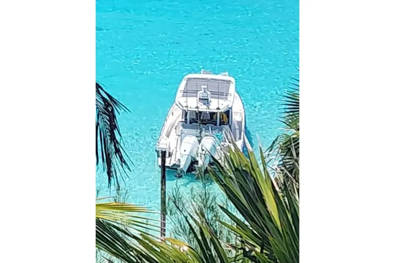 Slide: The Image of 2018 Axopar 37 Sun-Top boat on clear turquoise water, surrounded by palm leaves. - 3