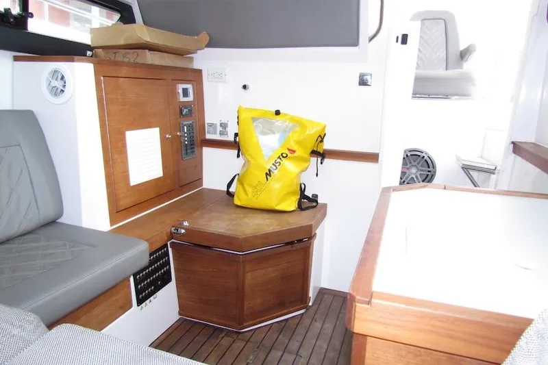 Slide: The Image of Interior of 2018 Axopar 37 Sun-Top with yellow Musto bag on wooden cabinet. - 32
