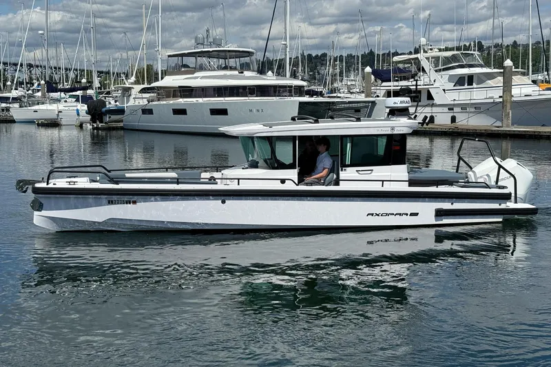 The Image of 2022 Axopar Brabus 28 Cabin boat docked in a marina with other yachts. - 0