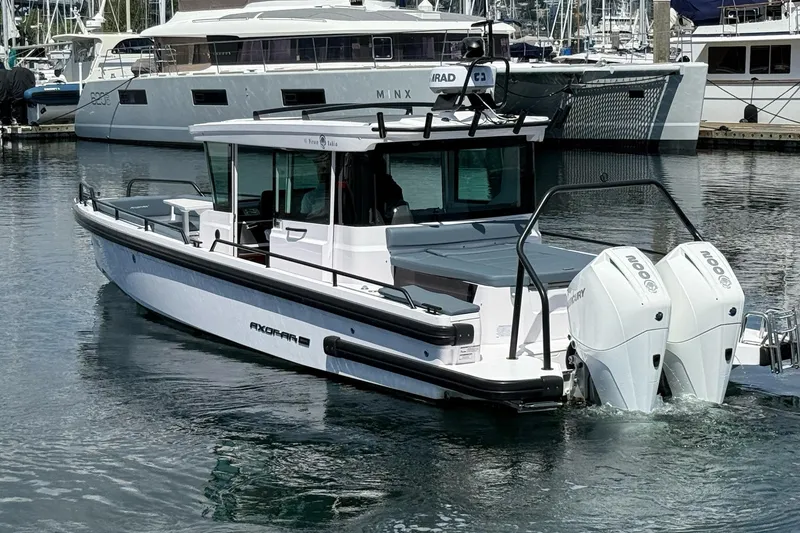 Slide: The Image of 2022 Axopar Brabus 28 Cabin boat docked in marina, featuring twin outboard engines. - 13