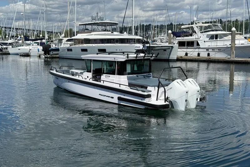 Slide: The Image of 2022 Axopar Brabus 28 Cabin boat in marina, surrounded by yachts and calm water. - 14