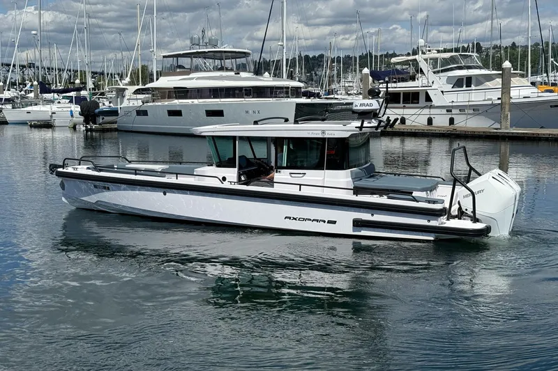 Slide: The Image of 2022 Axopar Brabus 28 Cabin boat docked in a marina with other yachts. - 15