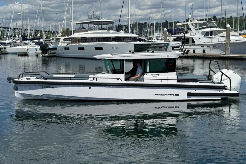 Slide: The Image of 2022 Axopar Brabus 28 Cabin boat docked in a marina with other yachts. - 17