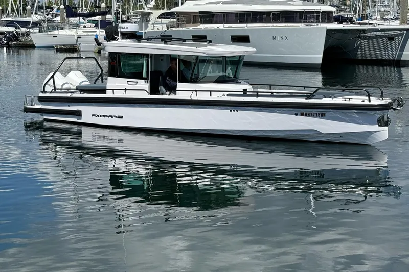 Slide: The Image of 2022 Axopar Brabus 28 Cabin boat docked in marina, reflecting on water. - 4