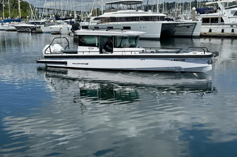 Slide: The Image of 2022 Axopar Brabus 28 Cabin boat docked in a marina, surrounded by other vessels. - 5