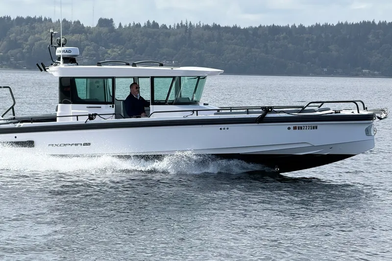 Slide: The Image of 2022 Axopar Brabus 28 Cabin cruising on a scenic lake with forested background. - 1