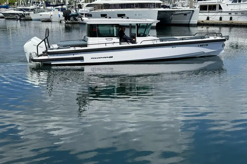 Slide: The Image of 2022 Axopar Brabus 28 Cabin boat cruising in a marina, reflecting on calm water. - 7