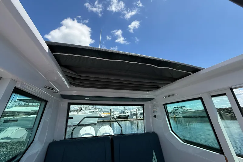 Slide: The Image of 2022 Axopar Brabus 28 Cabin interior with open sunroof, docked at marina. - 73