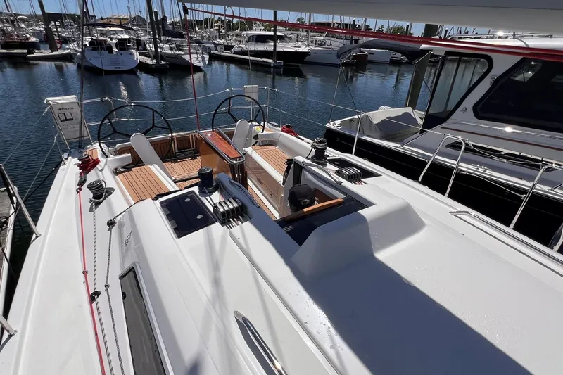 Slide: The Image of 2019 Dehler 34 sailboat docked at marina, showcasing sleek deck and dual steering wheels. - 26