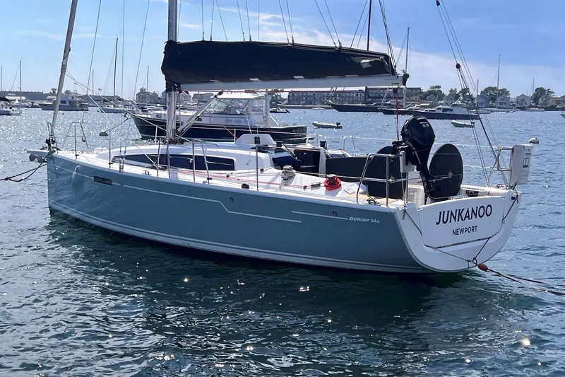 Slide: The Image of 2019 Dehler 34 sailboat named "Junkanoo" docked in a sunny harbor. - 1
