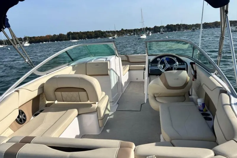 Slide: The Image of 2020 Regal 23 OBX boat interior with beige seating, steering wheel, and open water view. - 2