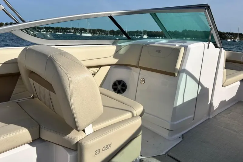 Slide: The Image of 2020 Regal 23 OBX boat interior with beige seating and windshield, docked on a sunny day. - 5