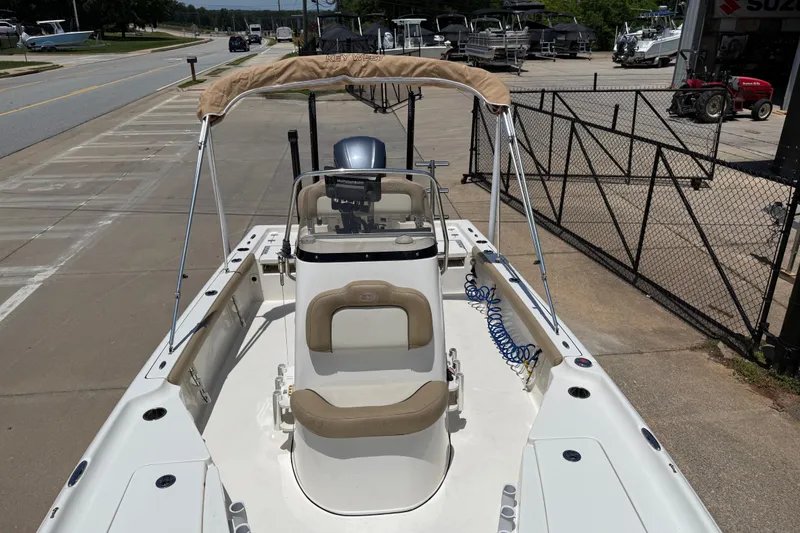 Slide: The Image of 2019 Key West 230 Bay Reef boat with beige seating and canopy, parked on concrete. - 18