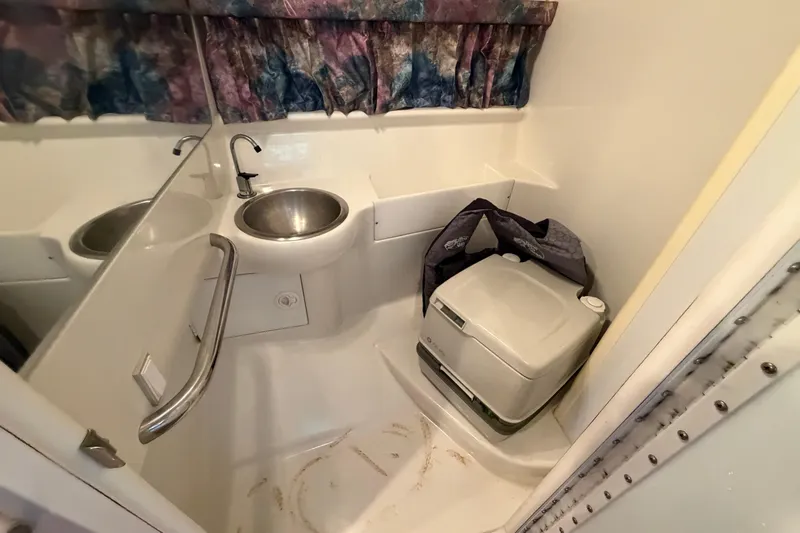 Slide: The Image of Compact bathroom in a 1998 Formula 280 Sun Sport boat with sink and portable toilet. - 18